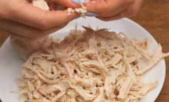 ต้มเนื้อไก่ในน้ำเกลือ พักให้เย็น แล้วแยกออกเป็นเส้นใย คุณยังสามารถตัดเป็นเส้นได้