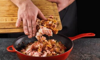 Acum puneți în tigaie pulpa scoasă de pe coaste și fâșii de slănină. Sarați și piperați ingredientele după gust. Se amestecă și se prăjește totul timp de aproximativ 10 minute.