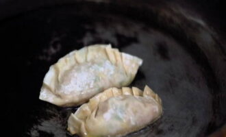 We knijpen de randen stevig vast, waardoor de halffabrikaten een langwerpige vorm krijgen. Doe de dumplings in een koekenpan met verwarmde plantaardige olie en bak ze 2 minuten, giet er dan een ½ kopje water bij en houd afgedekt totdat de vloeistof is verdampt.