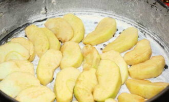 Ilagay ang kalahati ng mga hiwa ng mansanas sa ilalim ng kawali.