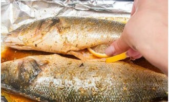 Đặt những lát chanh vào bên trong cá chẽm. Để cá ngấm gia vị khoảng 30 phút.