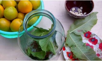 Clătiți un borcan de trei litri cu sifon; nu este nevoie să îl sterilizați. Clătiți condimentele. Curățați cățeii de usturoi și tăiați în jumătate. Pregătiți roșiile. Pune jumătate din condimente și usturoi pe fundul borcanului.