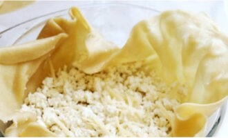 Bôi dầu vào chảo chịu lửa tròn và đặt các bánh sao cho phủ kín đáy và các cạnh rủ xuống. Đặt phô mai bào vào giữa.