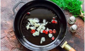 Hetta upp vegetabilisk olja i en stekpanna och tillsätt vitlökskivorna och chiliringarna utan kärnor.