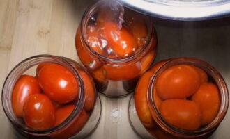 Sterilizați borcanele și capacele curate prin orice mijloace. Așezați roșiile compact în borcane, umpleți complet cu apă clocotită, acoperiți cu capace și lăsați timp de 15 minute.