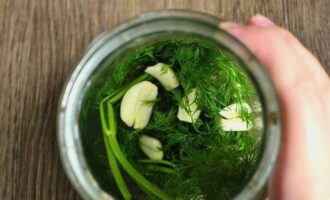 Đặt các lát tỏi và một bó thì là đã rửa sạch trước đó vào đáy lọ.