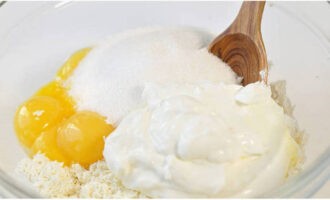 Afegiu els rovells, la crema agra, dos tipus de sucre granulat a la massa en forma de pasta i barregeu. Afegiu els rovells, la crema agra, dos tipus de sucre granulat a la massa en forma de pasta i barregeu.