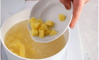 Tillsätt samtidigt potatiskuber i den kokande buljongen och koka i 10 minuter. Lägg nu en matsked potatis i skålen och mosa den med resten av vitlöken, löken, samt finhackad salladslök och dill.