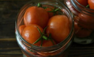 Col·loqueu aquí els tomàquets rentats i perforats. Col·loqueu els grans de pebre i les fulles de llorer per sobre i aboqueu aigua bullint durant 20 minuts. Després, escorreu l'aigua i afegiu-hi la marinada dolça. Per a això, bull aigua amb sucre i sal, i finalment afegim el vinagre. Tanquem les peces de treball amb una tapa, les girem cap per avall, les emboliquem en una manta i les deixem fins que es refredin completament.