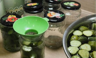 Pune castraveții în borcane destul de compact și folosind o pâlnie specială. Pe măsură ce umpleți, acoperiți borcanele cu capace.