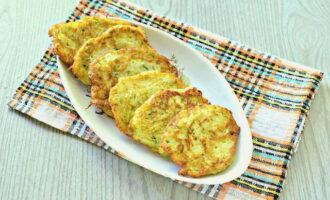 Primer transferiu els deliciosos panellets de carbassó i patates preparats en una paella sobre tovallons de paper per treure l'excés d'oli, i després serviu per esmorzar, afegint-hi crema agra. Bona gana! 
