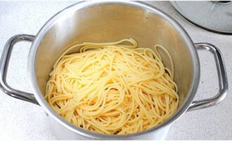 Ibuhos ang 50 ML ng sabaw ng pasta. Alisan ng tubig ang spaghetti sa isang colander at agad na ibalik ito sa kawali, dahil mahalagang panatilihin itong mainit.