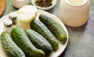 Het bereiden van plakjes komkommer (ringen) voor de winter is heel eenvoudig en gemakkelijk! Leg de groenten op een werkblad, inclusief gepelde uien en kruiden.