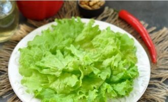 Rupem frunzele de salată în bucăți mici cu mâinile și le distribuim pe fundul unui vas de servire.