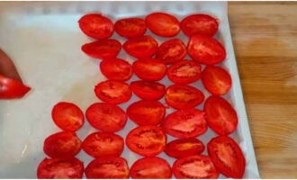 Cobriu una safata de forn amb paper i untem una mica amb oli vegetal. Col·loqueu-hi les meitats de tomàquet, amb el costat tallat cap amunt.