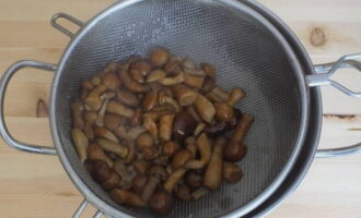 Giet de gekookte honingchampignons af in een vergiet.