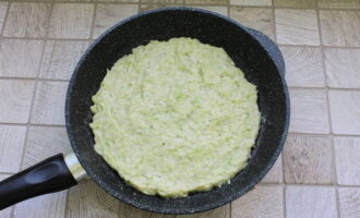 După ce încălziți o tigaie cu ulei vegetal, distribuiți baza de pizza, nivelând-o cu o spatulă.