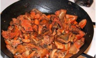 Voeg gekookte champignons toe aan de uien. Meng het mengsel en bak ongeveer 25 minuten.