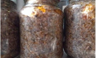 Plaats mierikswortelblaadjes en knoflook op de bodem van een gesteriliseerde pot, vul de container met de champignonbereiding en giet de resterende plantaardige olie in de pan. Rol op en laat volledig afkoelen. 