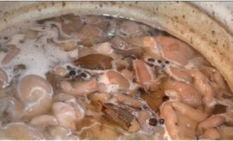 Lutuin ang marinade sa pamamagitan ng pagsasama ng tubig na may asin, asukal at pagdaragdag ng paminta at bay leaf. Pakuluan ang marinade at lutuin ng 5 minuto, at pagkatapos ay ibaba ang pinakuluang mantikilya. Pagkatapos kumukulo, pakuluan ang mantikilya sa loob ng 5 minuto. Magdagdag ng suka essence at patayin ang apoy. Punan ang mga isterilisadong garapon ng mga kabute.