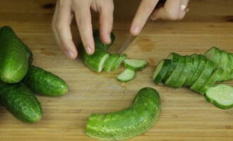 Cum să prepari o salată delicioasă pentru iarnă? Clătiți bine castraveții proaspeți cu apă rece și, dacă nu sunt doar din grădină, îi puteți înmuia în apă cu gheață cu câteva ore înainte. Apoi tăiați-le în cercuri de cel mult 0,5 cm grosime.