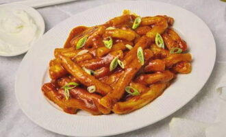 Placera beredd teokbokki i koreansk stil hemma i portionerade tallrikar, strö över hackad salladslök och servera med gräddfil. Smaklig måltid! 