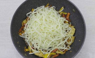 Voeg de gekookte udon-noedels toe aan de groenten en de kip, meng goed en kook het gerecht nog 2-3 minuten op laag vuur, zodat de saus de noedels verzadigt.