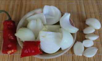 Balatan ang sibuyas at bawang. Gupitin ang sibuyas sa malalaking piraso. Putulin ang ilang mainit na paminta.
