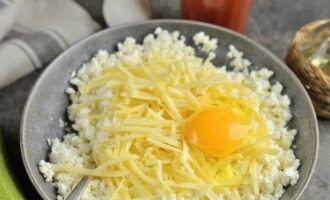 Măcinați brânza de vaci cu orice conținut de grăsime folosind o furculiță. Trei brânzeturi mari. Adăugați majoritatea așchiilor de brânză în brânză de vaci. Sparge oul. Se condimentează cu usturoi tocat, sare și piper.