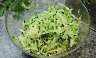Coarsely lagyan ng rehas ang hugasan at tuyo na zucchini. Ilagay sa isang mangkok, magdagdag ng asin at mag-iwan ng 10 minuto.