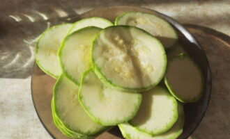 We wassen de courgette en snijden hem in dunne cirkels, en drogen hem vervolgens tegen vocht met keukenpapier.