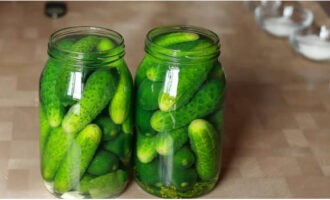 Vul de potten met komkommers. Vul met vooraf bereid kokend water. Dek af met deksels en laat 10 minuten staan.