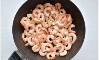 Tillsätt räkor till vitlök. Stek i cirka tre minuter och strö över en blandning av torkade örter och mald svartpeppar.