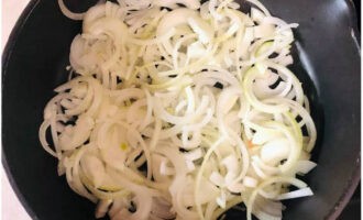 Lägg en rad lökringar i en hög stekpanna.