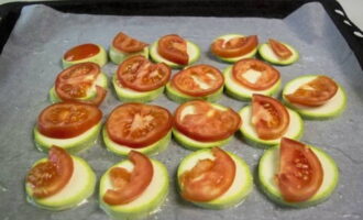Ilagay ang baking paper sa isang baking sheet. Kung kinakailangan, balutin ng langis. Hindi ito kailangan ng siliconeized parchment. Nilagay ko ang zucchini. Ilagay ang mga kamatis sa itaas.