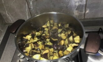 Turnați ulei de măsline într-o cratiță sau o cratiță. Puneți vinetele aici și fierbeți-le sub capac timp de 15 minute, amestecând din când în când.