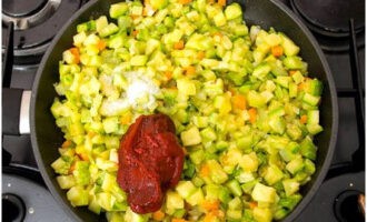 Passats 5-7 minuts, afegiu-hi els daus de carbassó per fregir, amaniu les verdures amb sucre granulat, sal i pasta de tomàquet. 