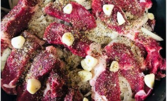 Det sista lagret ska vara kött. Krydda med salt, peppar och andra kryddor. Sätt strösocker och häll ättiksyra. Skär vitlöken i skivor och lägg ovanpå.