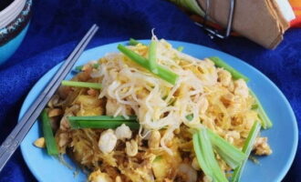 Servera Pad Thai varm, toppad med jordnötter, salladslök och böngroddar. Smaklig måltid!