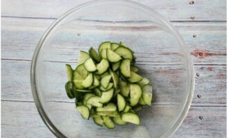 Ang Georgian salad ay inihanda nang mabilis at madali. Hugasan ang pipino, gupitin sa manipis na kalahating bilog at ilagay sa isang malalim na mangkok.