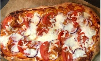 Bestrijk de goudbruine bodem met geraspte tomaten. Leg hier de gehakte verse tomaten, uien en geraspte zachte kaas. Bak nog eens 6 minuten.