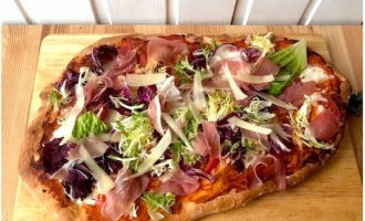 We halen de traktatie uit de oven. We vullen het aan met salademix, prosciutto en plakjes Parmezaanse kaas.