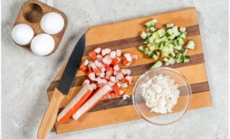 Gupitin ang mga crab stick, pinakuluang itlog at pipino sa malalaking piraso ng pantay na sukat.