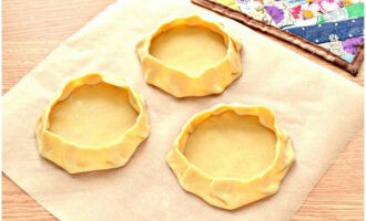 Tiếp theo, từ mỗi chiếc bánh dẹt, chúng ta tạo thành những khoảng trống để nướng lại. Nâng các cạnh của bánh lên và cố định chúng. Đặt chúng trên một tấm nướng bánh.