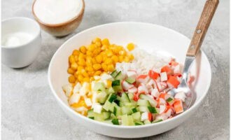 Ilagay ang mga tinadtad na sangkap sa isang mangkok ng salad at magdagdag ng de-latang mais na may pinalamig na bigas.