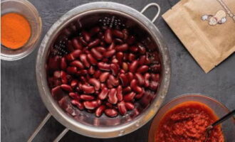 Vi späder ut tomatpulvret till en pastakonsistens, öppnar en burk bönor, lägger bönorna i en sil och sköljer under rinnande vatten.