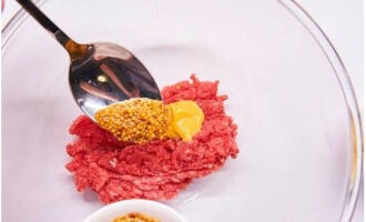 Trong một cái bát sâu lòng, trộn thịt bò xắt nhỏ và hai loại mù tạt.