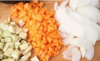 Gupitin ang natitirang mga sibuyas sa kalahating singsing, at mga karot at talong sa mga medium-sized na cube. Gupitin ang natitirang mga sibuyas sa kalahating singsing, at mga karot at talong sa mga medium-sized na cube.