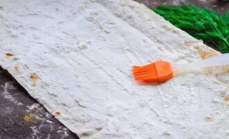 Bred ut ett lager lavash och smörj med ett generöst lager ostmassa.