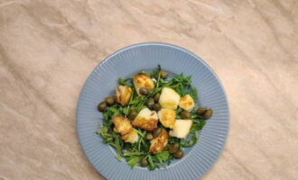 Col·loqueu la rúcula en un plat de servir, col·loqueu el formatge molt bé i decoreu-ho amb tàperes. Afegiu lleugerament sal i aromeu amb suc de cítrics.
